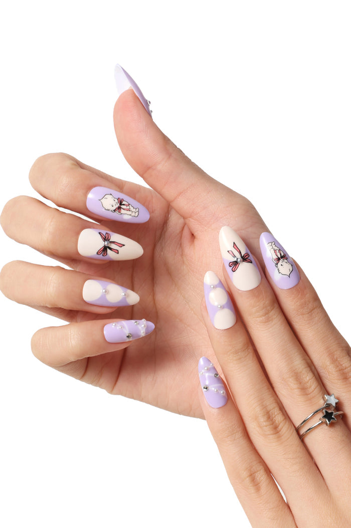 Purple and white stiletto press-on nails with Kewpie character and bow designs, pearl accents