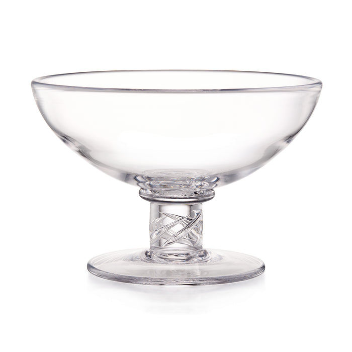 Clear glass serving dish with a wide shallow bowl, a patterned stem, and a round base, photographed on a white background.