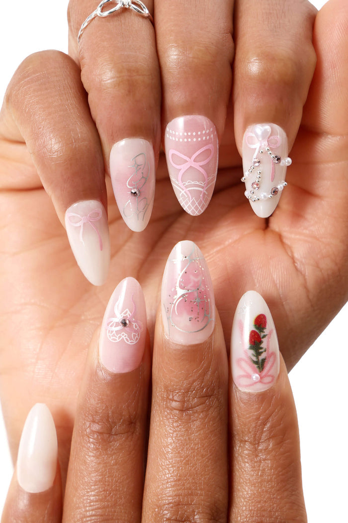 Almond press-on nails with pink bows, pearls, and strawberry design.
