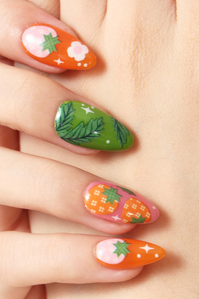 Press-on nails with strawberry and leaf designs, featuring orange, pink, and green colors.