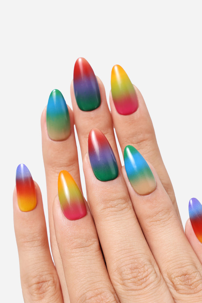 Close-up of a hand wearing almond-shaped press-on nails with a vibrant rainbow gradient design.