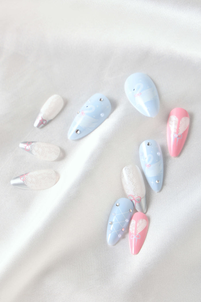 Swan Lake almond press-on nails with delicate swan, pearl, and lace designs on pastel blue and pink.