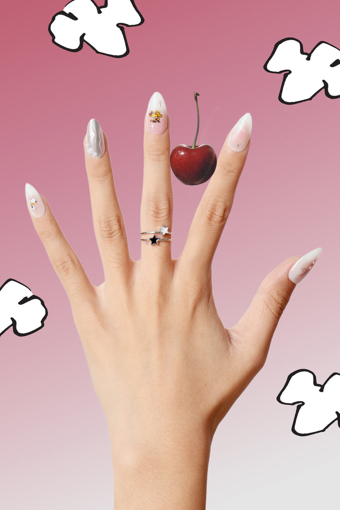 Almond press-on nails featuring Snoopy and Woodstock designs, with pastel swirls and a cherry accent.