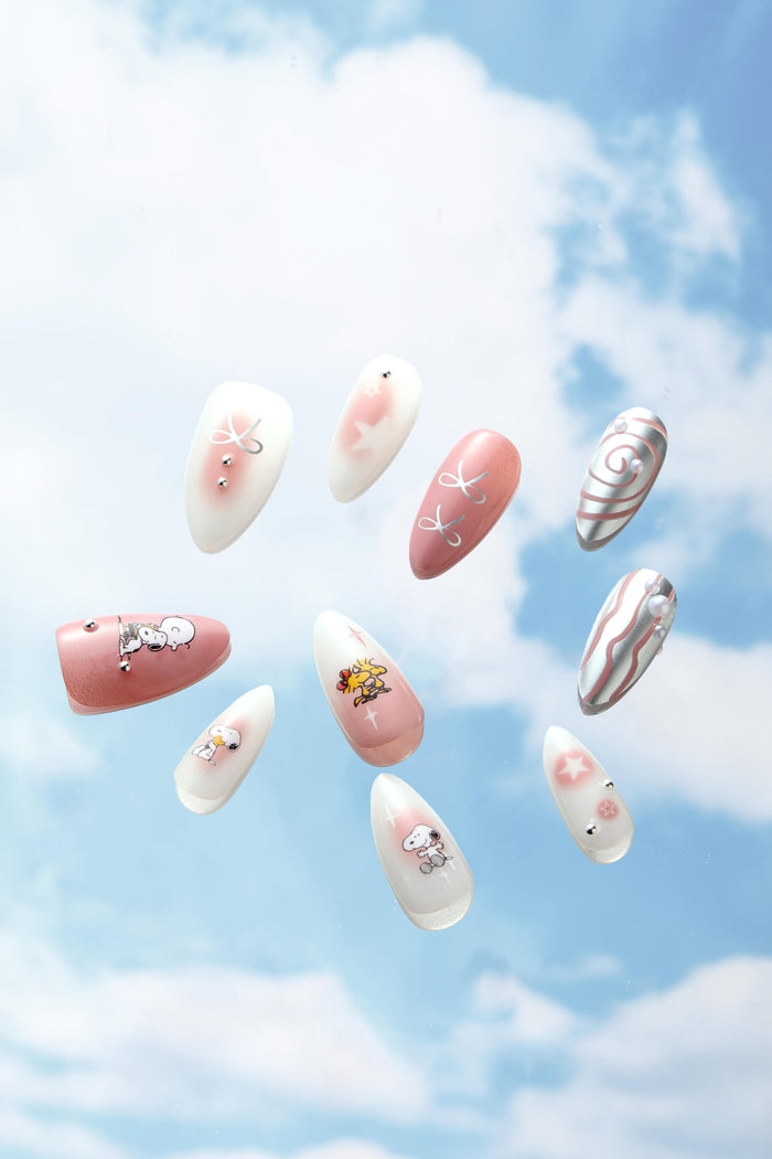 Almond press-on nails featuring Snoopy and Woodstock designs on a pastel pink and white swirl background.