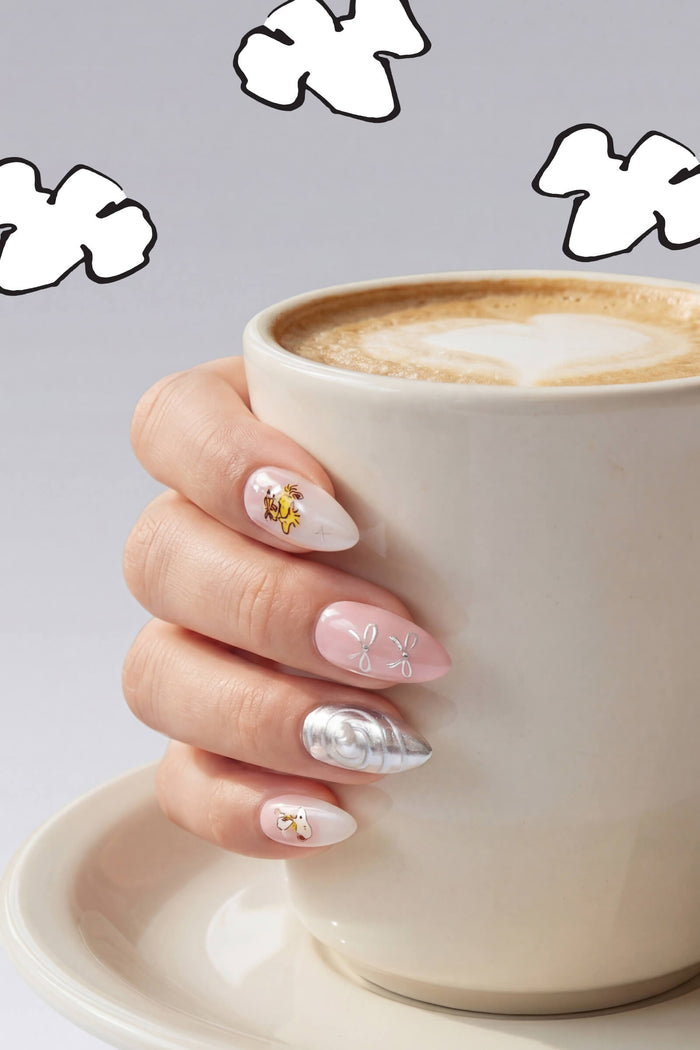 Almond press-on nails with Snoopy and Woodstock designs, featuring pink, white, and silver swirls.