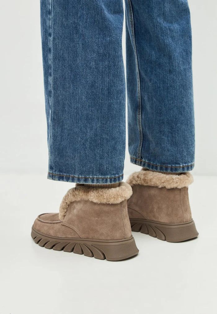 A stylish pair of women's taupe shearling-lined ankle boots, also known as Adriana brown boots, perfect for the colder seasons.
