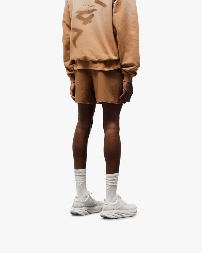 Man wearing rust shorts on a plain white background | Team 247 Aero Shorts in Rust | Running shorts with branded waistband and zip pockets | 247 Shorts | Represent Clo
