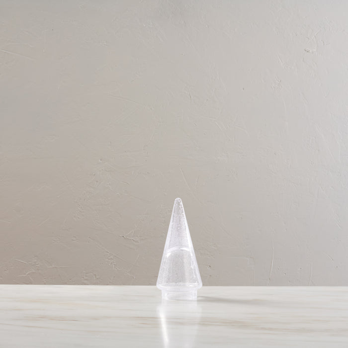 White conical tree-shaped candle with textured surface on white base.