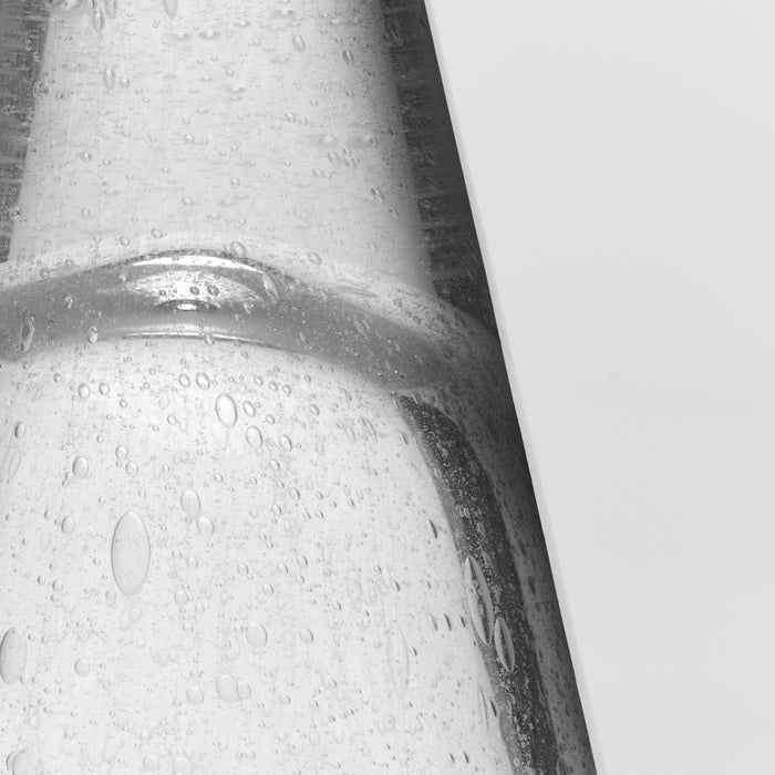 White conical tree candle with textured surface and moisture droplets, displayed at an angle.