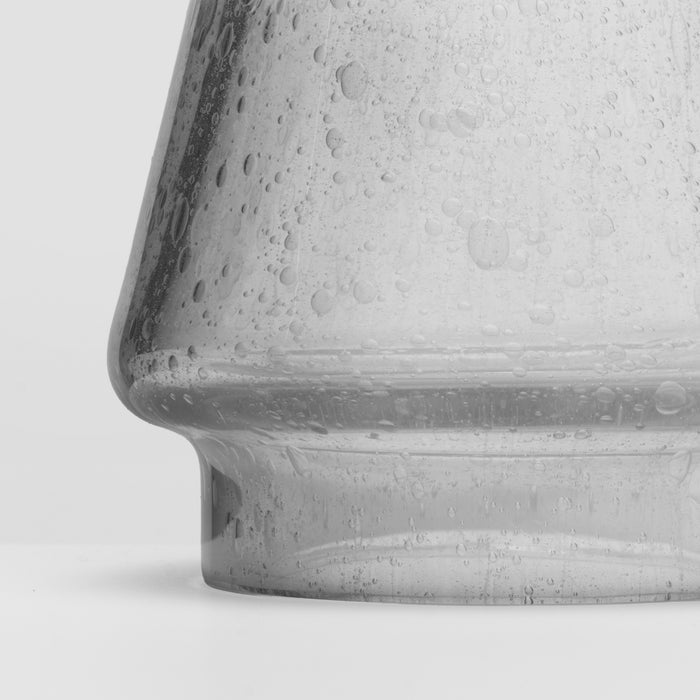 White speckled conical candle with textured surface and rounded base.