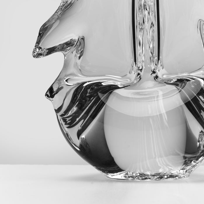 Clear glass deer figurine with antlers and a white cylindrical element, shown in black and white.