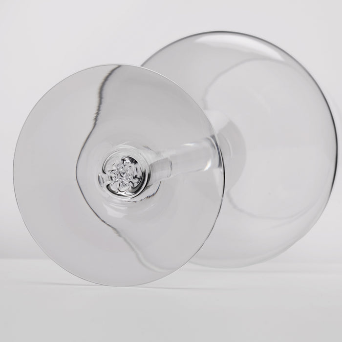 A close-up studio shot of a clear glass wine glass viewed from the bottom, showing the circular bowl and stem against a light gray background.
