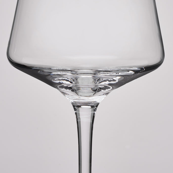 A close-up studio shot of a clear glass wine glass against a light gray background.