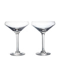 Two clear coupe glasses with wide bowls and thin stems on white background.
