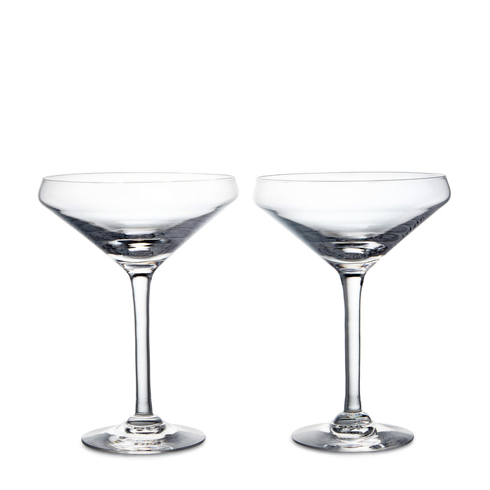 Two clear coupe glasses with wide bowls and thin stems on white background.
