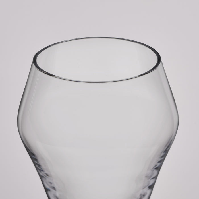 A close-up of a clear glass tumbler with a rounded, bulbous body and a textured base, shown against a neutral light gray background.