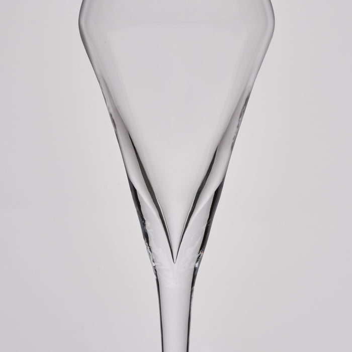 A clear glass champagne flute shown from the back against a light gray studio background.