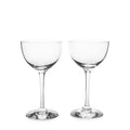 Two clear coupe glasses with thin stems and rounded bowls on a white background.