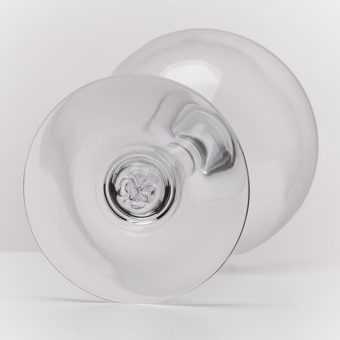 A clear glass goblet or wine glass shown from a bottom angle on a light gray studio background.
