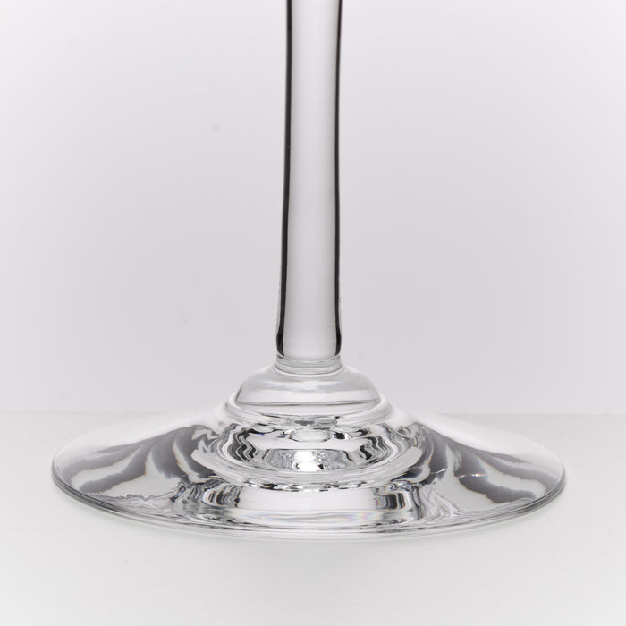 A close-up studio shot of a clear glass wine glass stem and wide circular base on a light gray background.