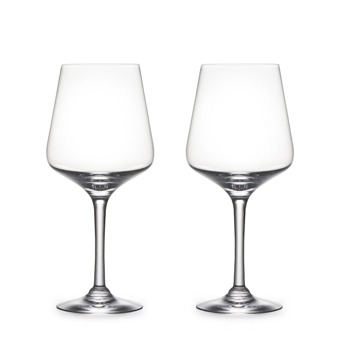Two empty clear wine glasses with tapered bowls and thin stems on white background.