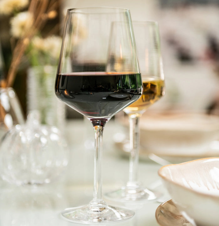 Two wine glasses on a table, one filled with red wine and one with white wine.