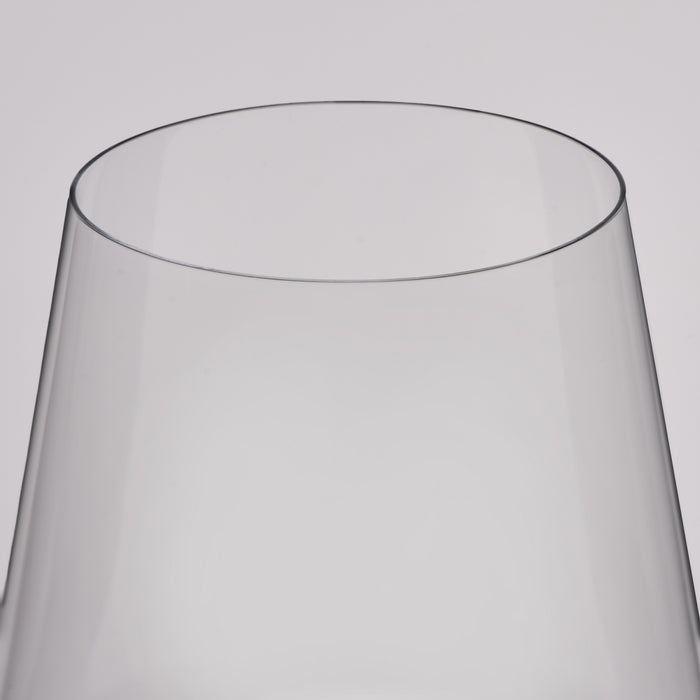A close-up of a clear glass vessel, likely a wine glass, showing the smooth curved edge of its transparent body against a light gray background.