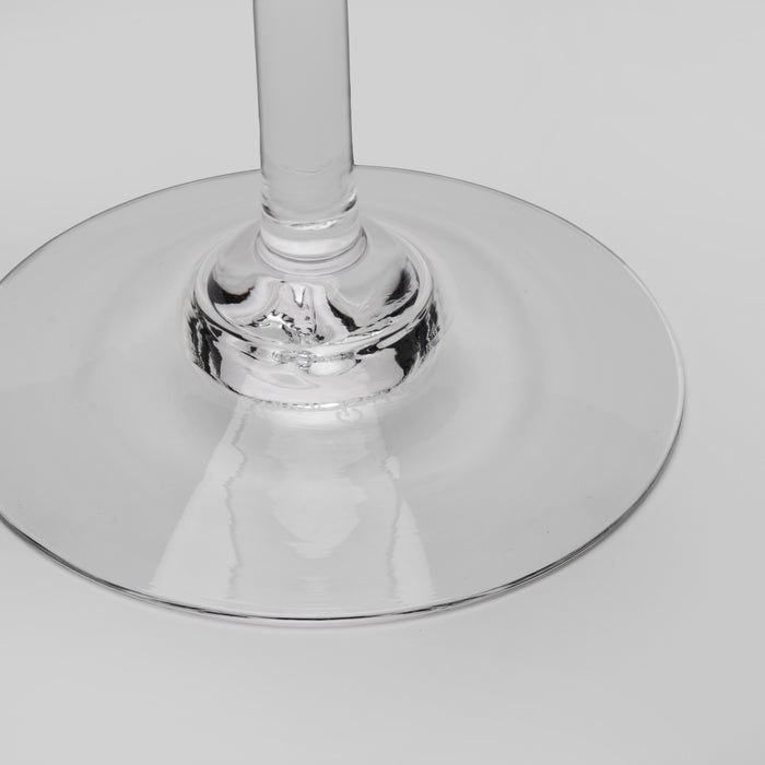Close-up of a clear glass wine glass base and stem on a light gray background.