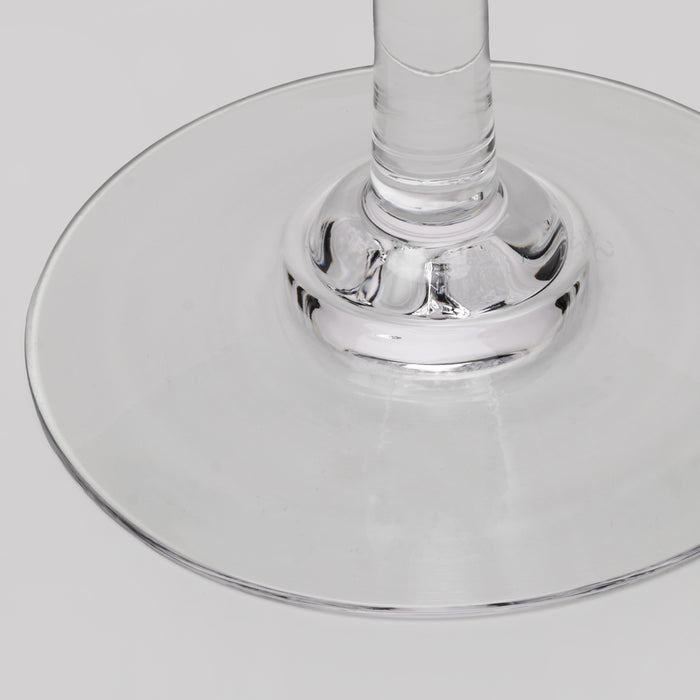 Close-up of a clear glass wine glass base and stem on a light gray background.