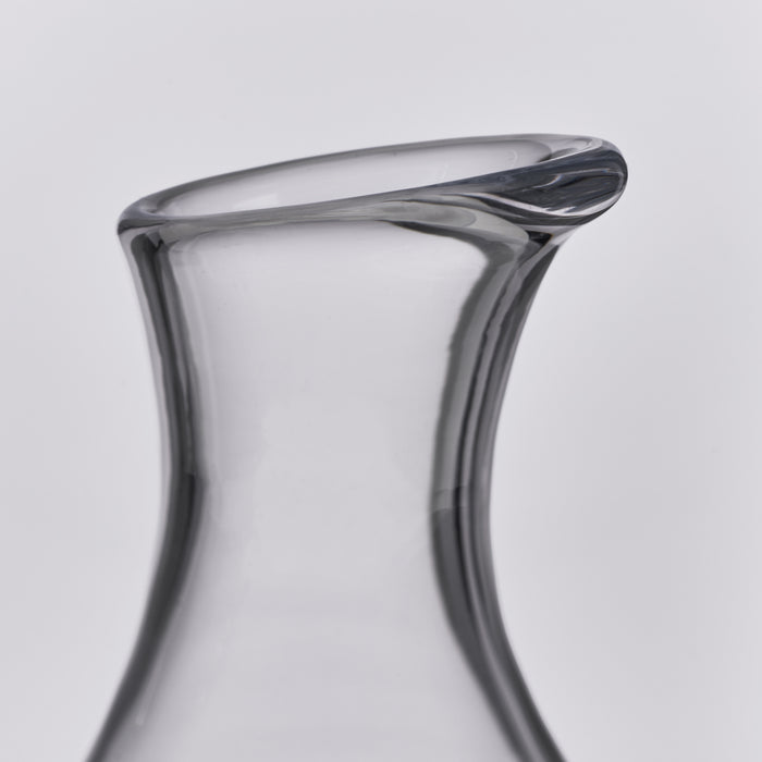 Clear glass wine decanter with curved sides and a dark marble stopper at the top.
