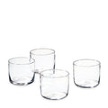 Four clear cylindrical drinking glasses with thick bases arranged in a group.