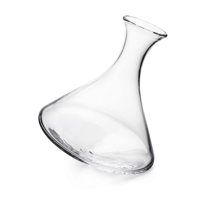 Clear glass wine decanter with curved body and angled pouring spout, tilted on rounded base.