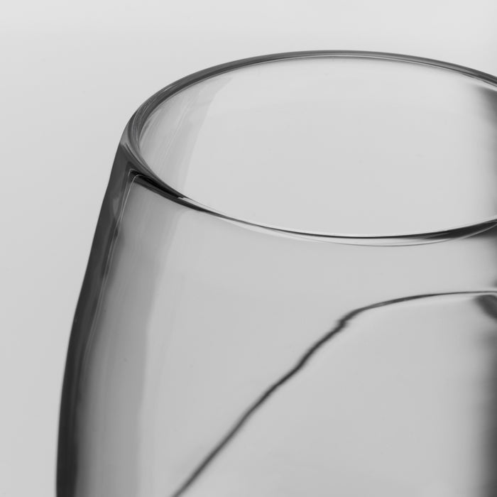 Close-up of a clear glass vessel, showing the curved rim on a light gray background.