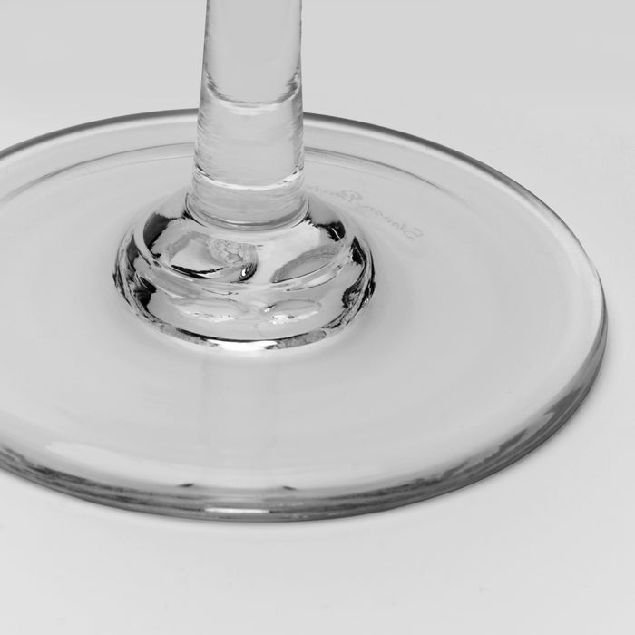Close-up of a clear glass wine glass base and stem on a light gray background.
