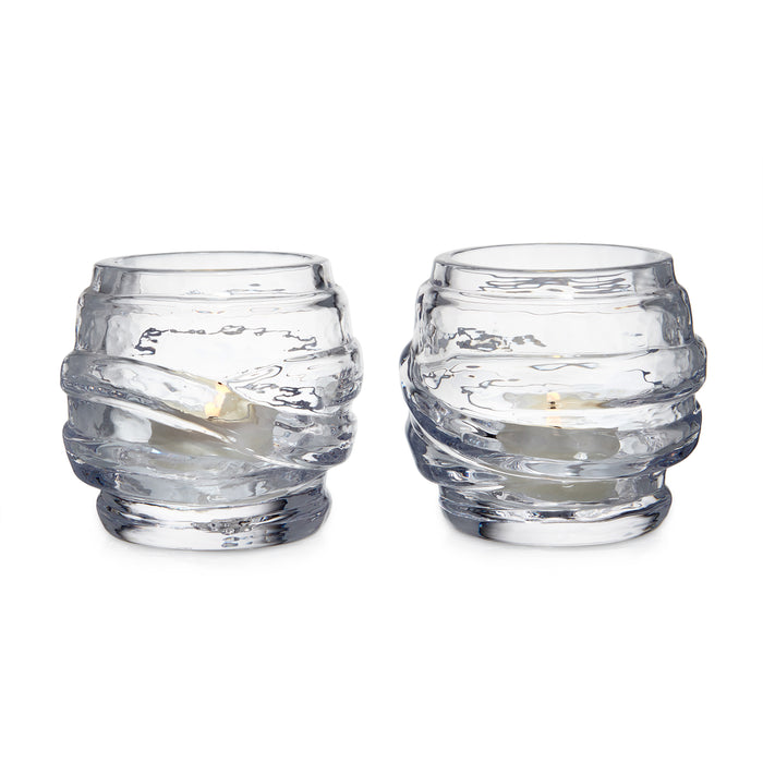 Two clear glass tealight holders with textured wrap design, each containing a small cream-colored candle.