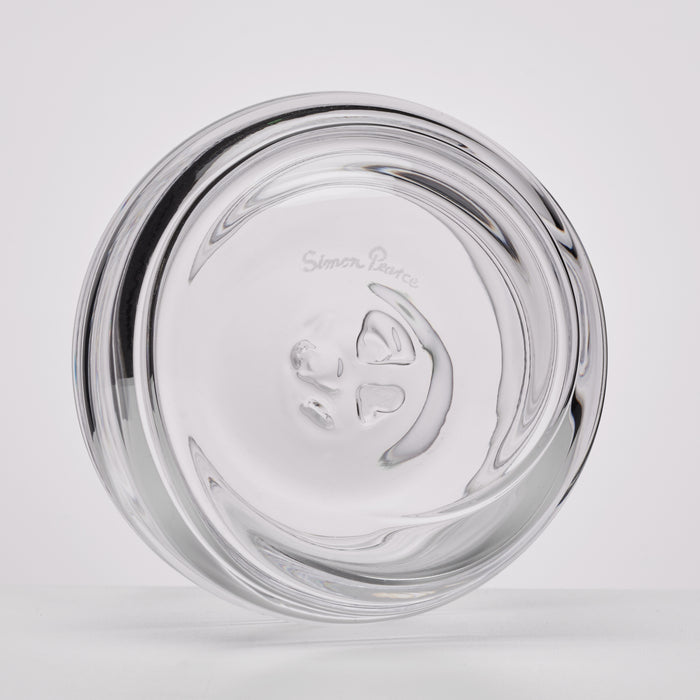 A clear glass ashtray with a sculptural, wavy design and the etched brand name Simon Pearce visible in the center, shown on a light gray background.