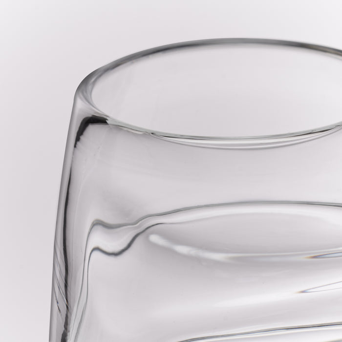 Close-up of a clear glass tumbler with a thick, rounded rim and smooth curved glass body on a light gray background.