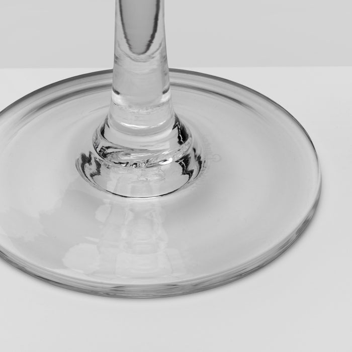 Close-up of a clear glass wine glass base and stem on a light gray background.