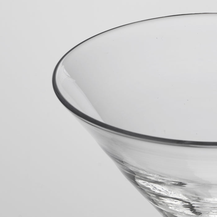 Clear glass stemless martini glass with curved bowl and dark rim, shown in close-up detail.