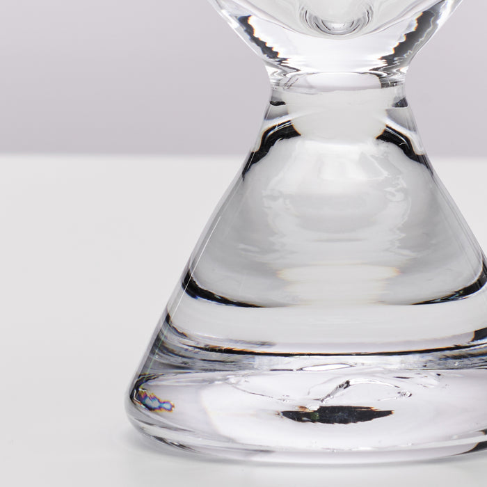 Clear glass stemless martini glass with wide bowl and narrow base, partially filled with liquid.
