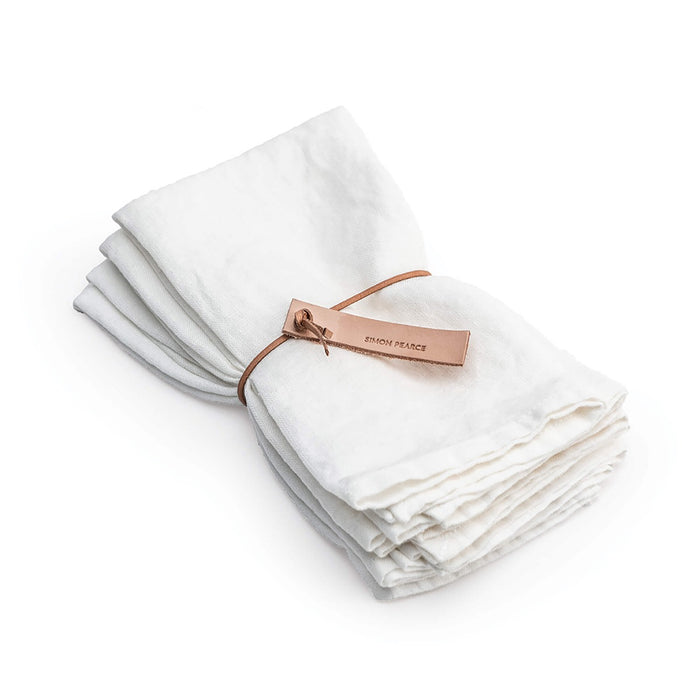 Four white linen napkins with hemmed edges, tied together with a copper-colored leather band.