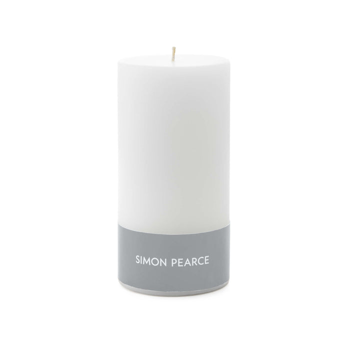 White cylindrical pillar candle with cream wick and gray band labeled "SIMON PEARCE" at base.