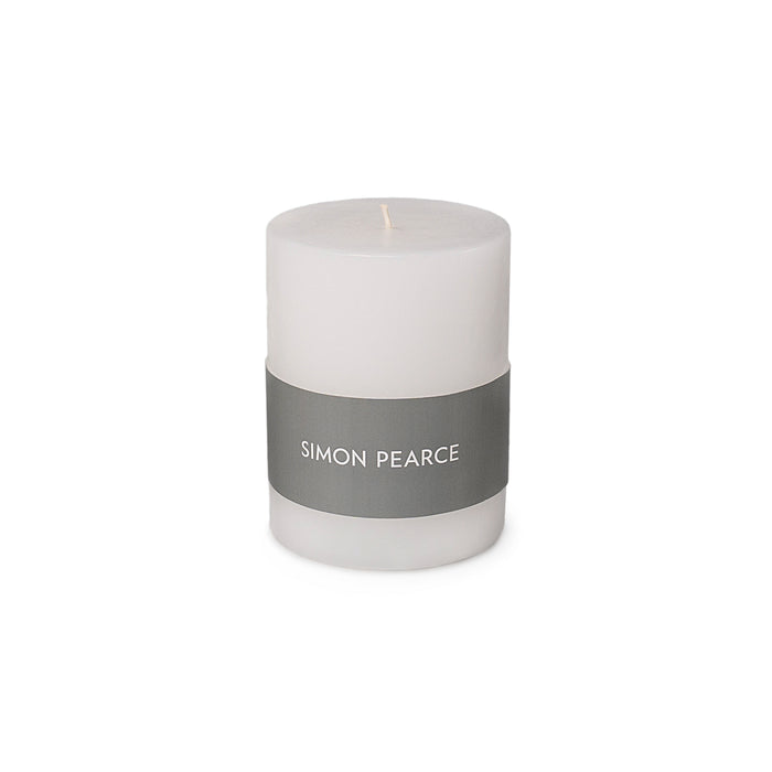 White cylindrical pillar candle with gray band label reading "SIMON PEARCE" and single wick.