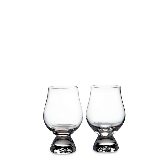 Two clear glass tasting glasses with tapered bowls and weighted bases.