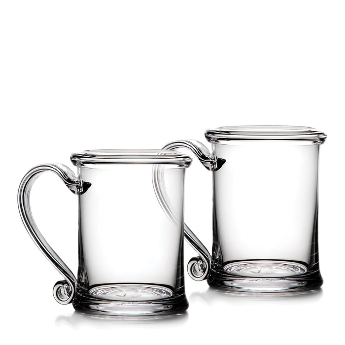 Two clear glass tankards with handles and circular base medallions.