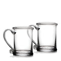 Two clear glass tankards with handles and circular base medallions.