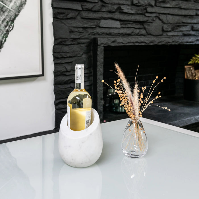 White marble wine chiller holding a bottle of white wine on a table.