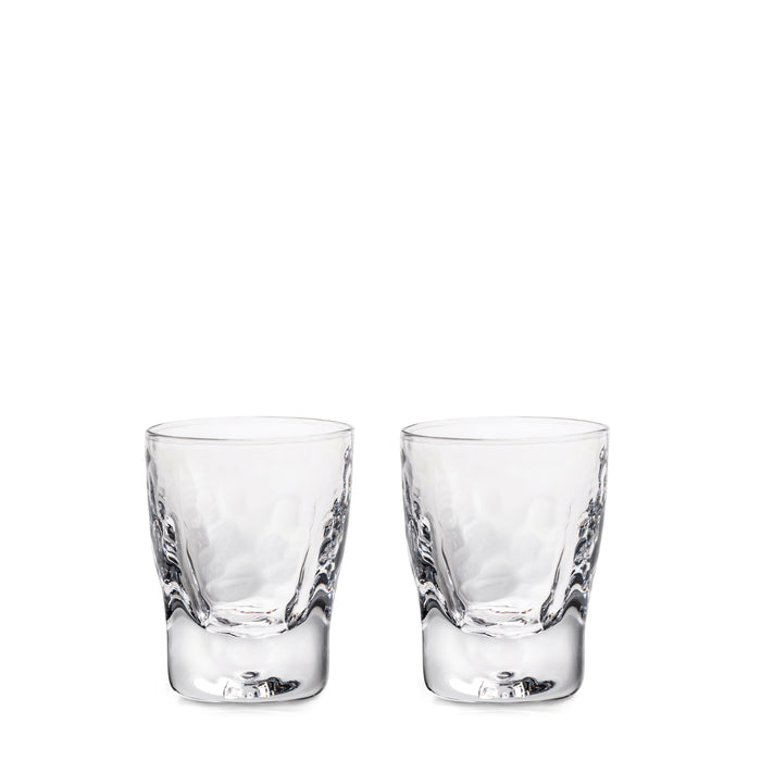 Two clear glass shot glasses with textured sides and reinforced bases.