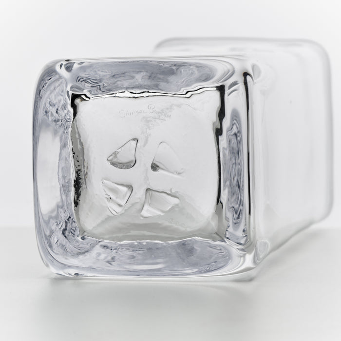 Clear glass carafe with ice cubes inside and a handle on the side.