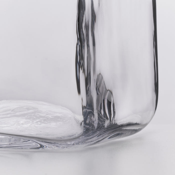 Clear glass decanter with curved sides and a rounded base against a white background.